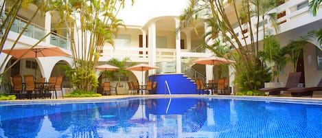Una piscina al aire libre, sillones reclinables de piscina