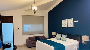 A bedroom with a bed, a sofa, a desk, and a projector screen. - Gran Costa Azul Hotel (Puerto Barrios)