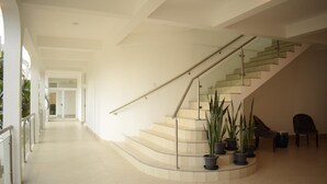 A spacious, modern interior with a curved staircase, potted plants, and a clear view of the adjacent room. - Gran Costa Azul Hotel (Puerto Barrios)