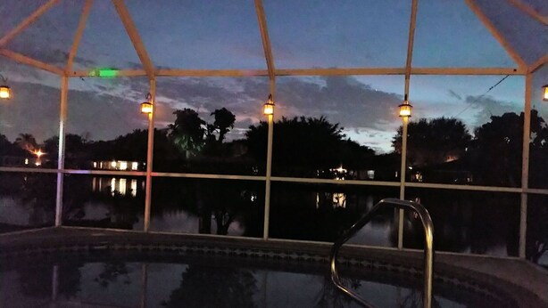 Ein Außenpool mit Glasveranda, umgeben von Bäumen und Blick auf eine ferne Stadtlandschaft.