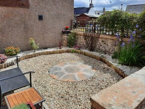 Un patio con mesa de piedra, asientos y zona de grava.