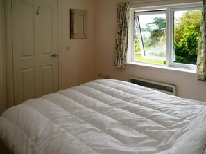 Une chambre à coucher avec un lit, une fenêtre avec des rideaux et une porte.