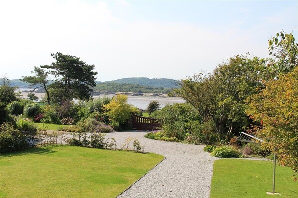 A pathway leading to a scenic view of a body of water, surrounded by lush greenery and a wooden bridge.