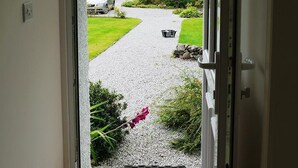 A doorway leading to a gravel driveway with a car parked on the side. - Seabank Cottage -  a cottage that sleeps 6 guests  in 3 bedrooms (Dalbeattie)