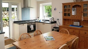 A kitchen with a dining table, chairs, a stove, oven, and a wooden cabinet. - Seabank Cottage -  a cottage that sleeps 6 guests  in 3 bedrooms (Dalbeattie)