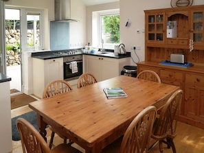 A kitchen with a dining table, chairs, a stove, oven, and a wooden cabinet.