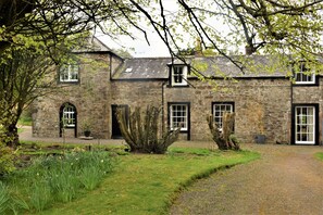 A stone building with multiple windows and a gravel path leading to the entrance. - The Stables -  a house that sleeps 14 guests  in 6 bedrooms (Kirkbean, Dumfries)