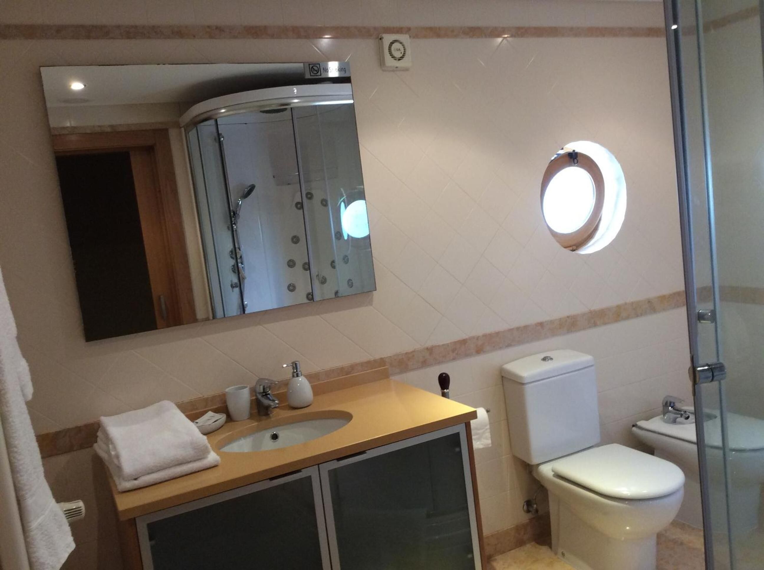 Een badkamer met een wastafel, spiegel, toilet en een douchecabine van glas.