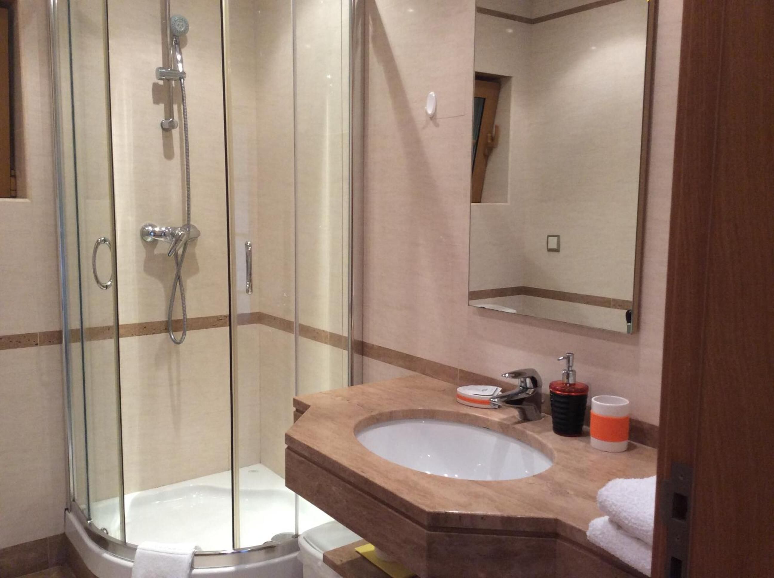 Un baño con ducha de vidrio, un lavamanos con encimera de mármol y un espejo sobre el lavamanos.