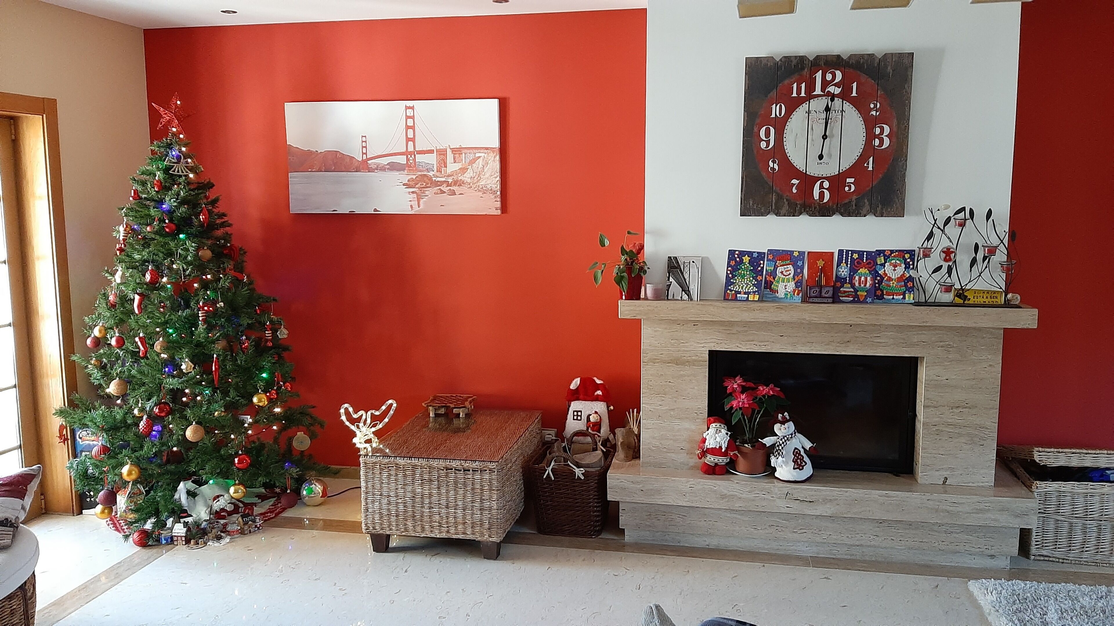 A living room with a Christmas tree, a fireplace, and a clock on the wall.