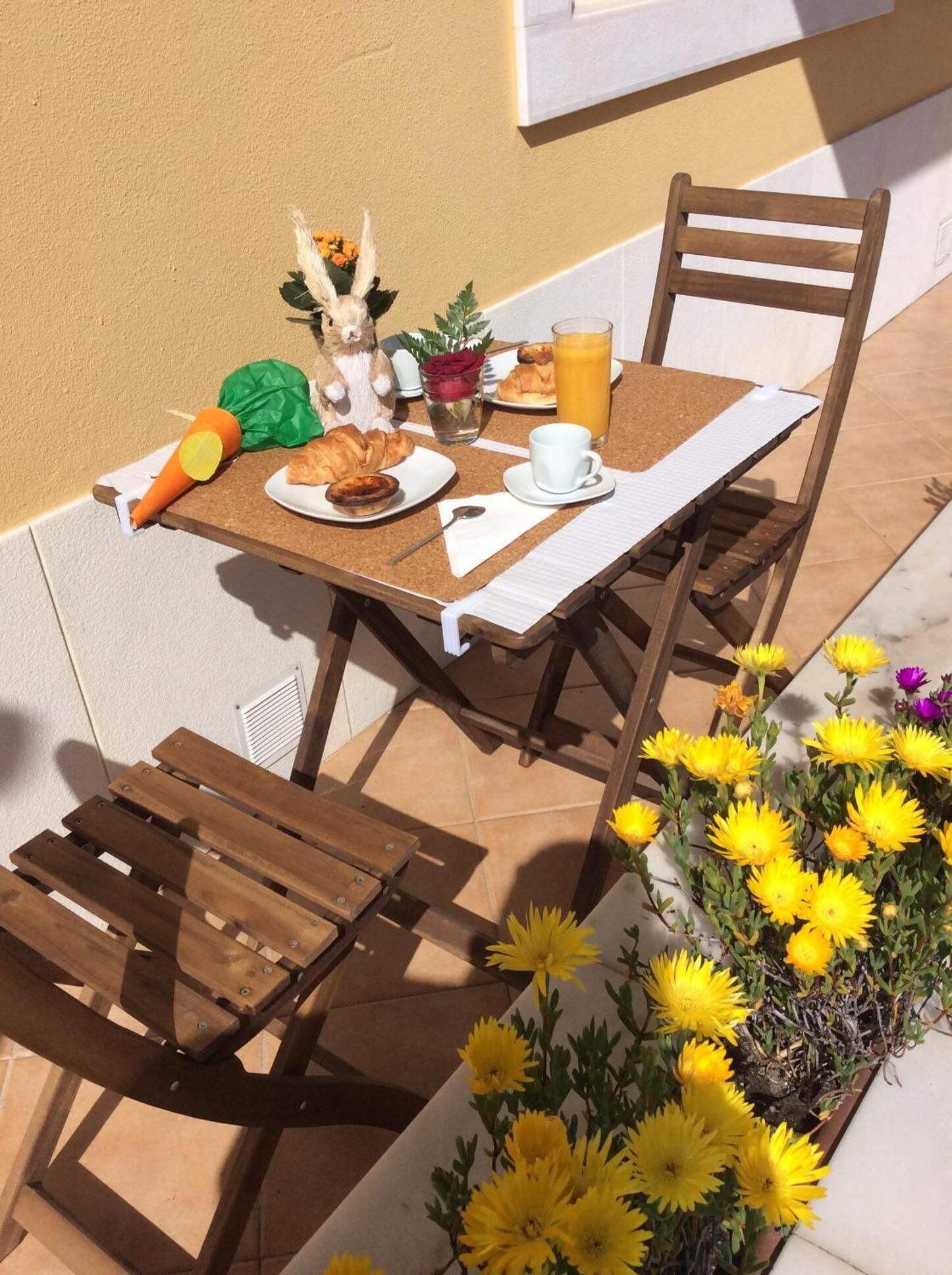 A table set with breakfast items, a chair, and a flower arrangement.