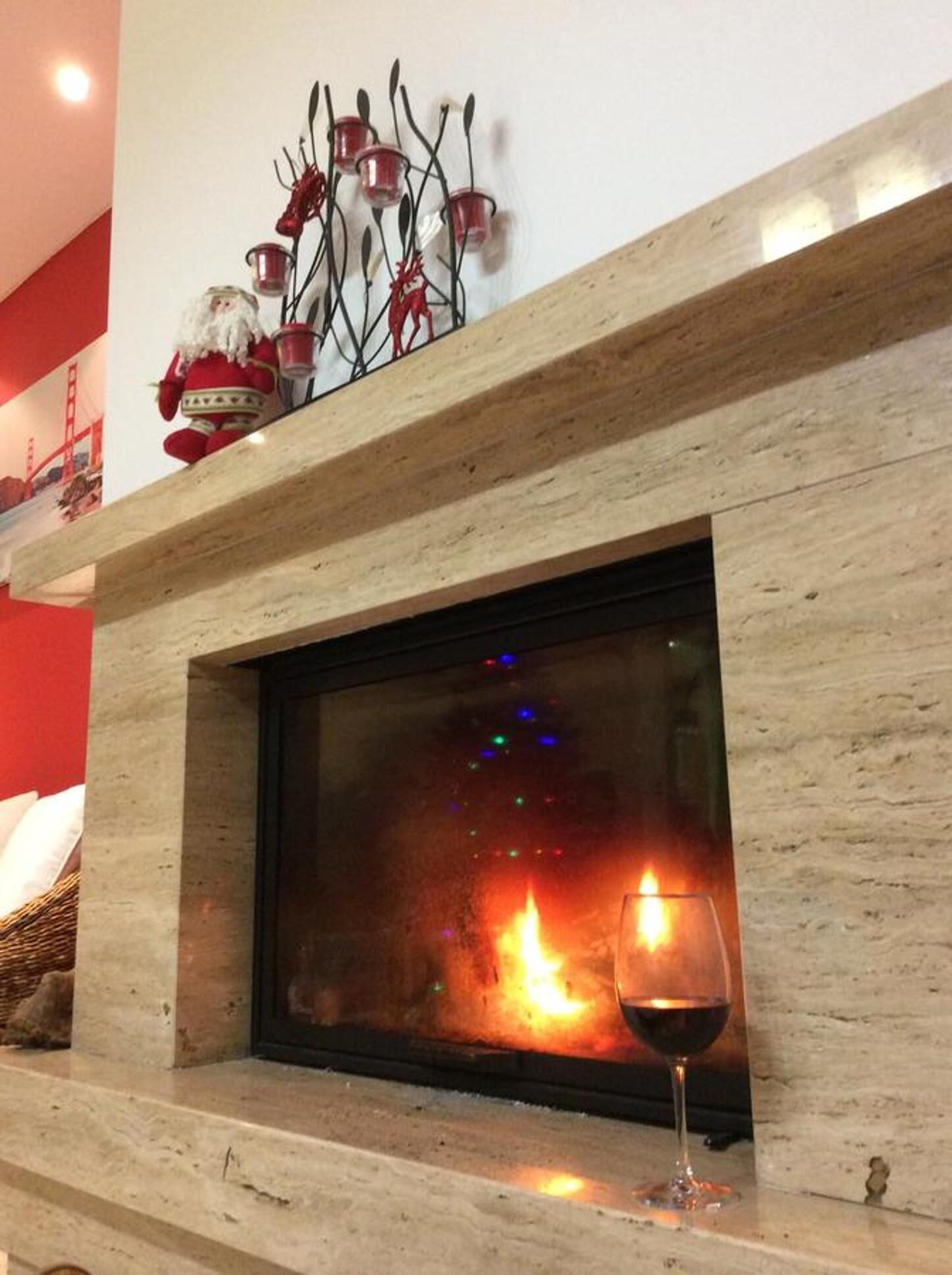A fireplace with a glass door, a glass of red wine, and a decorative metal piece above it.