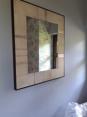 Un espejo en marco con papel tapiz floral en la pared.