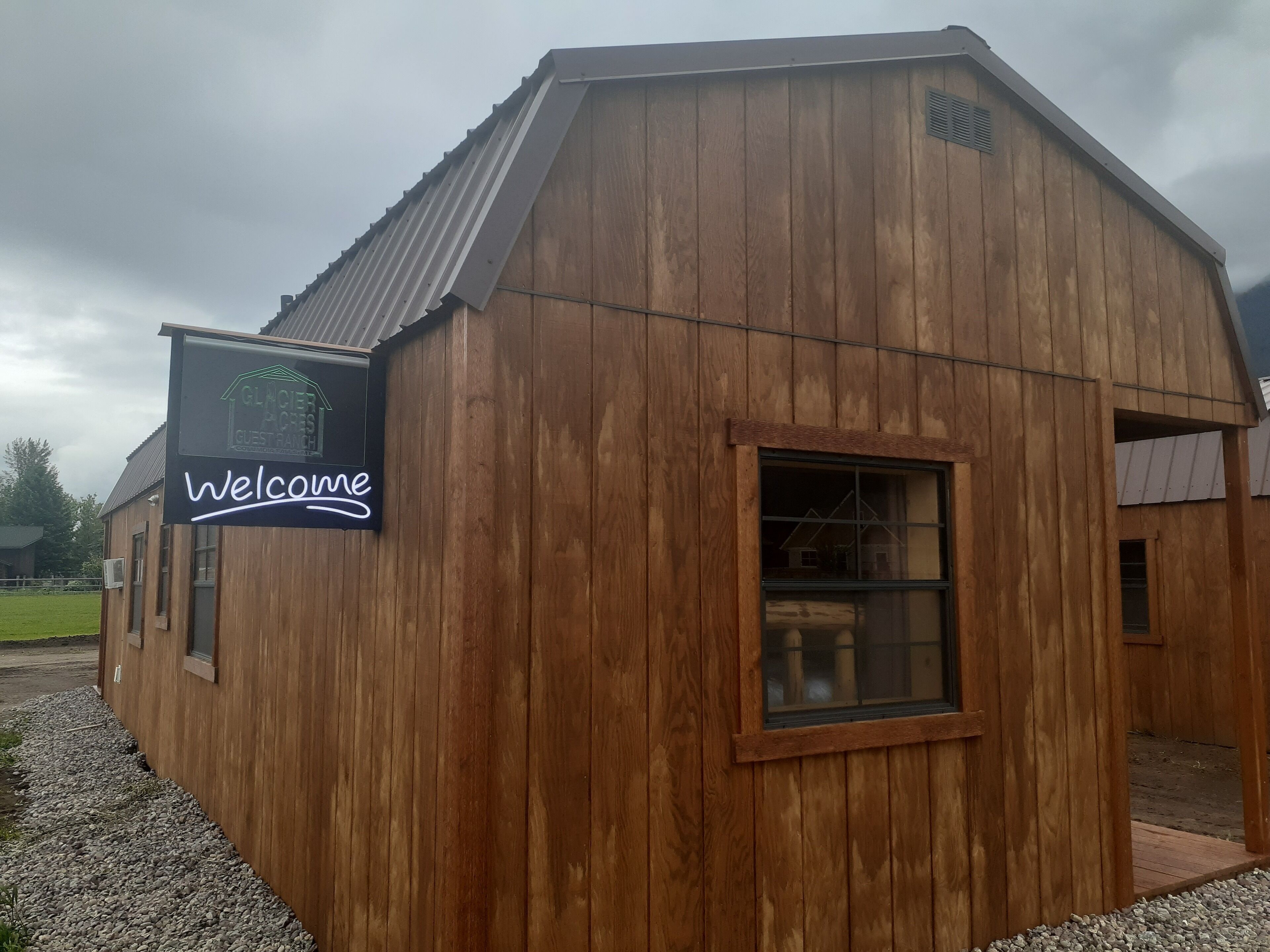 Un edificio de madera con un letrero que dice 'Welcome' y una ventana.