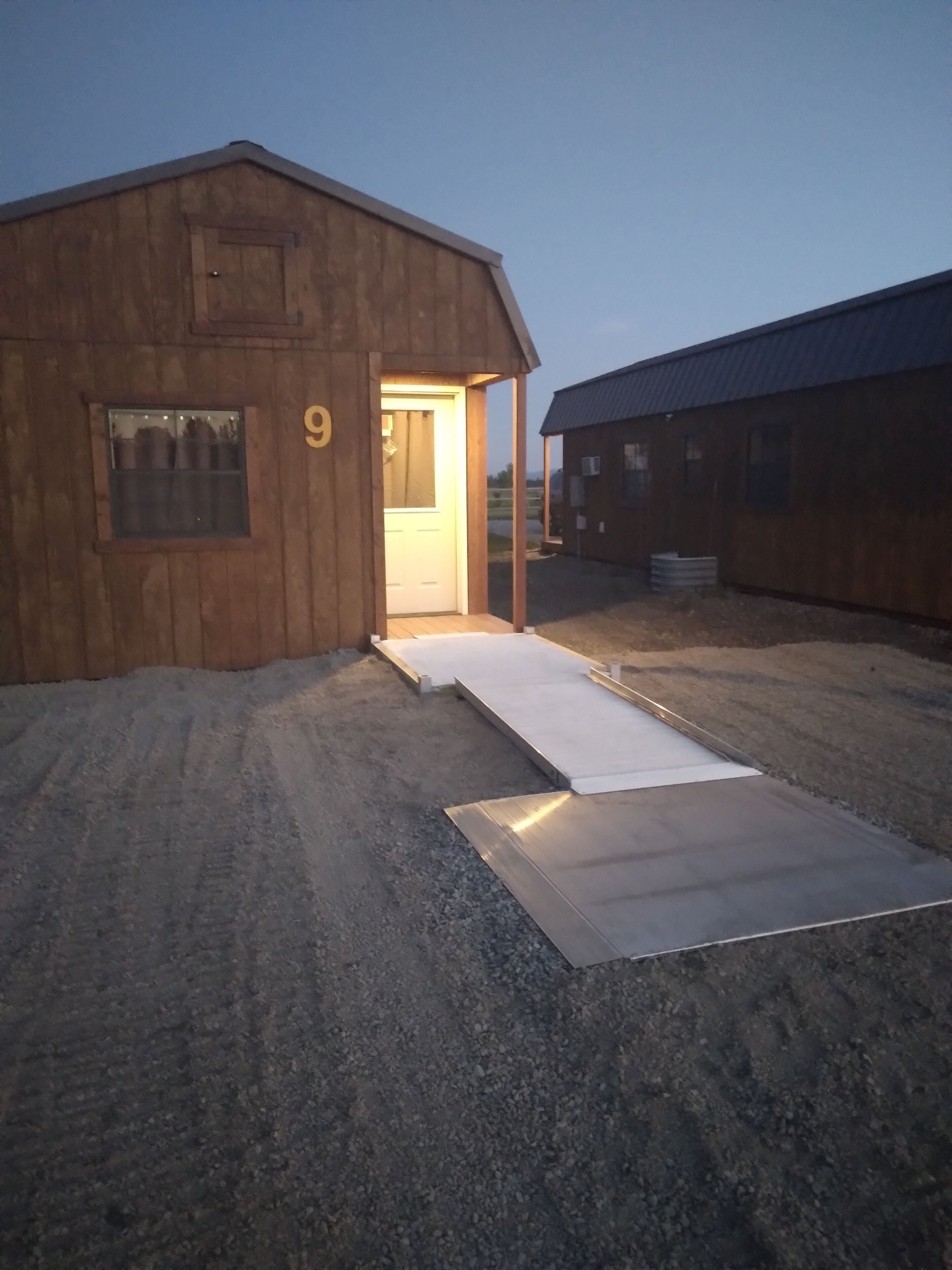 Un edificio de madera con el número '9' en la fachada, una puerta y una rampa que conduce a la entrada.