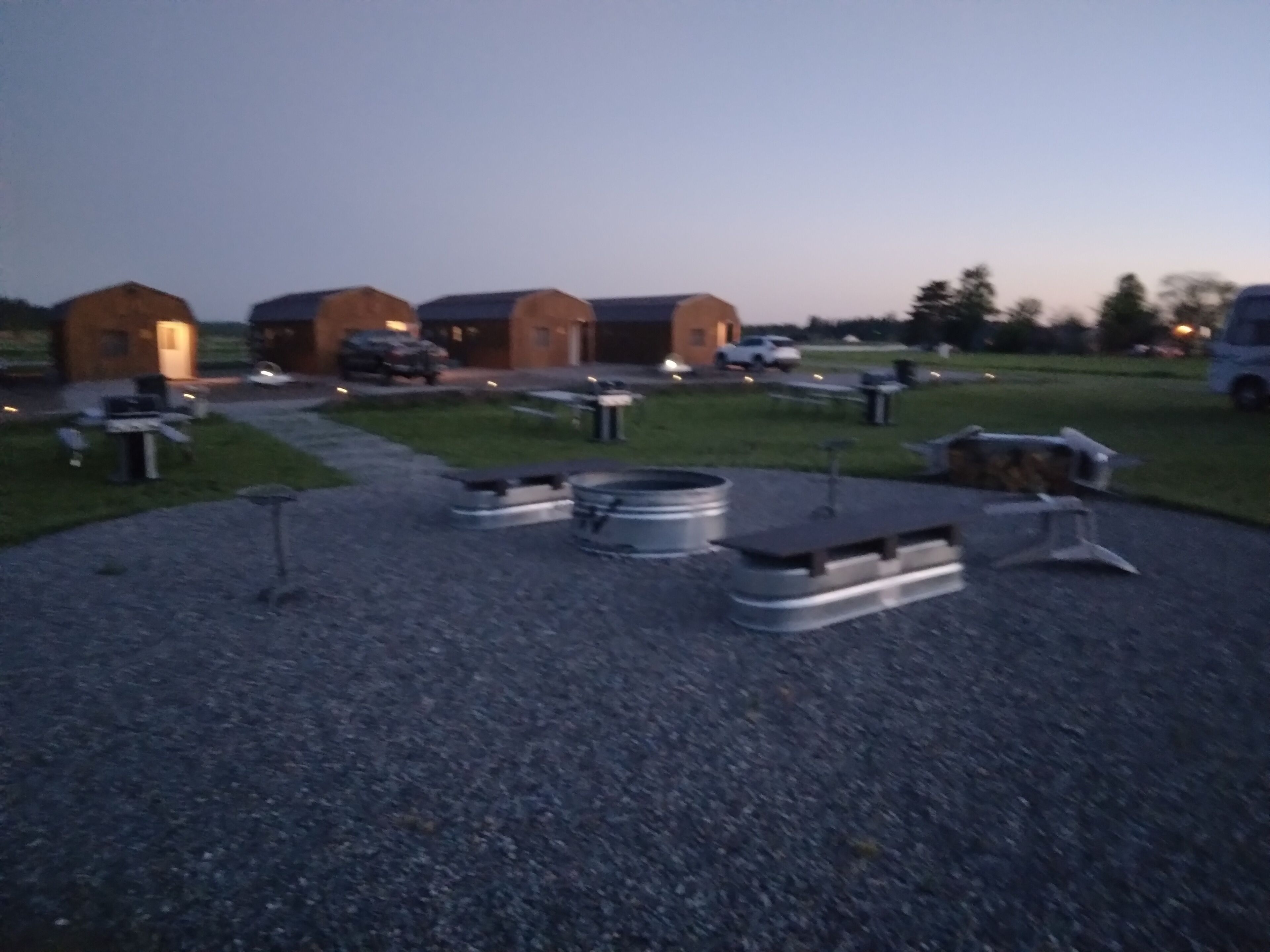 A gravel parking area with several metal structures, possibly for outdoor dining or storage.