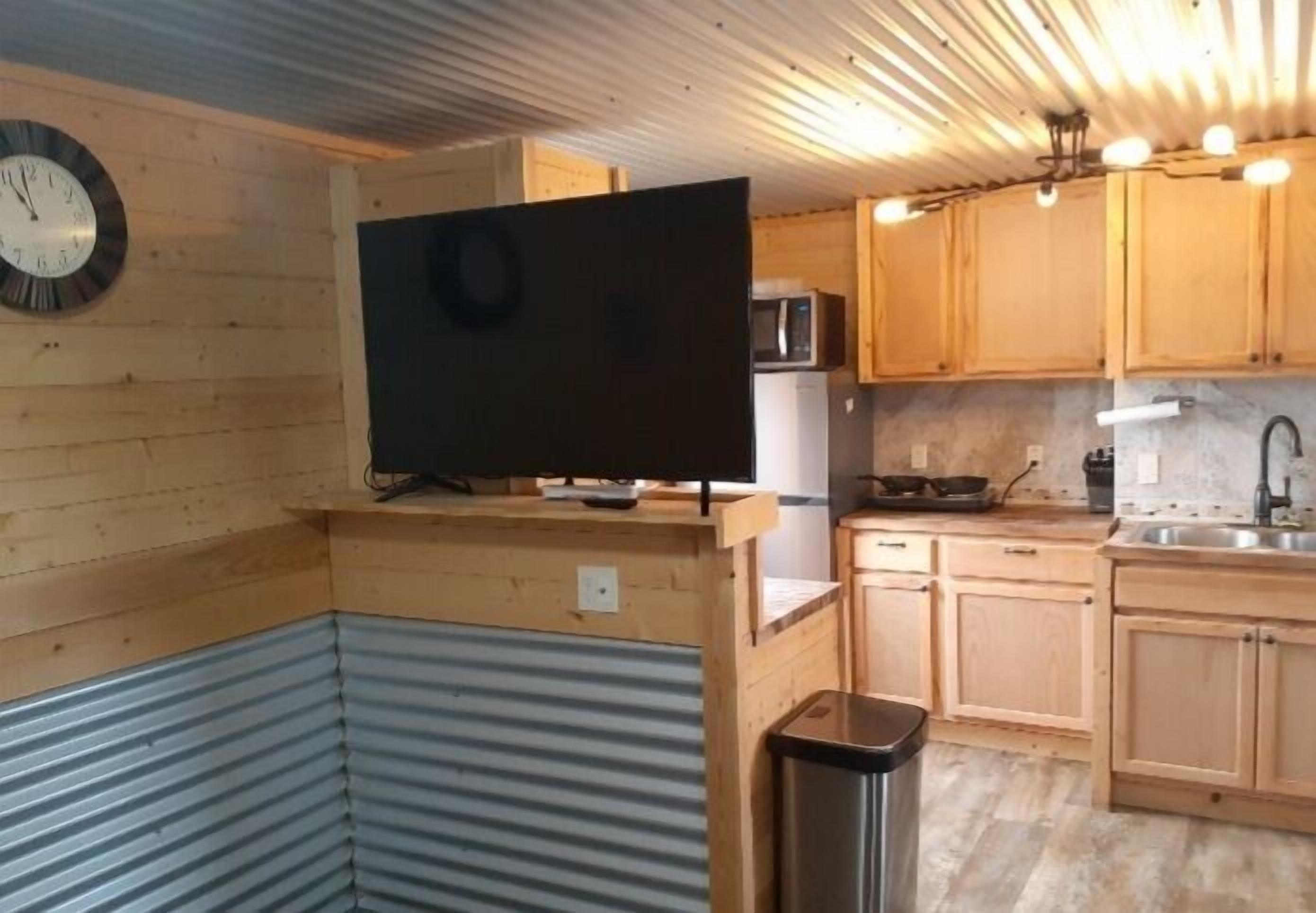 Cocina compacta con armarios de madera, un microondas y una encimera negra.