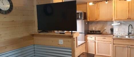 Cocina compacta con armarios de madera, un microondas y una encimera negra.