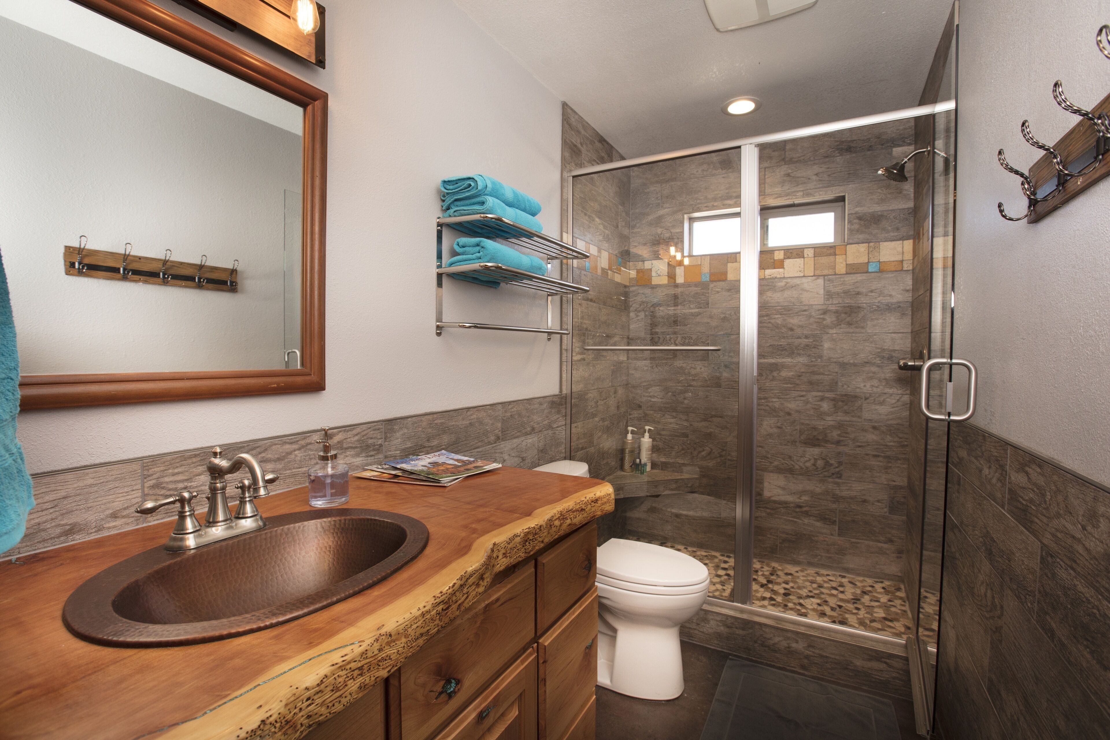 A bathroom with a wooden vanity, a sink, a mirror, a toilet, and a glass shower enclosure.