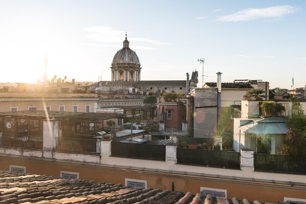 A cityscape with a prominent dome building, terracotta rooftops, and a clear sky.