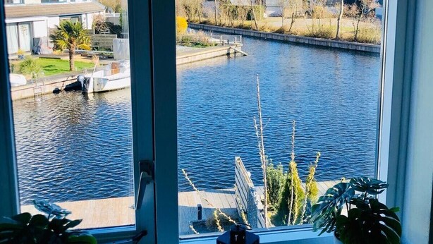 A view through a window of a river with houses in the background.