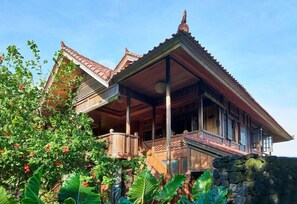 A traditional wooden house with a balcony, surrounded by lush greenery. - Jasri Bay Hideaway (Karangasem)