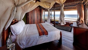 A bedroom with a bed, a nightstand, a bottle, and a view of the ocean. - Jasri Bay Hideaway (Karangasem)