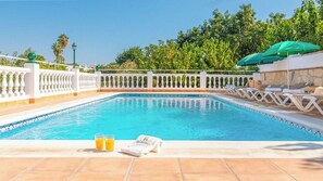A swimming pool with a white tiled deck, a white balustrade, and a green umbrella.