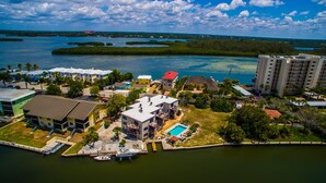 Ett flygbildsfoto av ett bostadsområde vid kusten med hus, en swimmingpool och en småbåtshamn med båtar.
