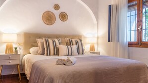 A neatly made bed with striped pillows, a bedside lamp, and a small plant on the nightstand.
