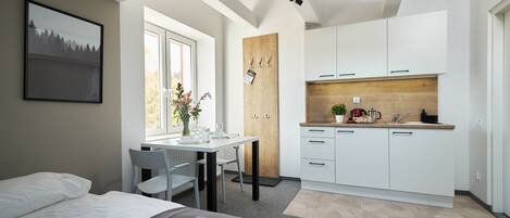 Un dormitorio moderno con cama, escritorio y kitchenette.