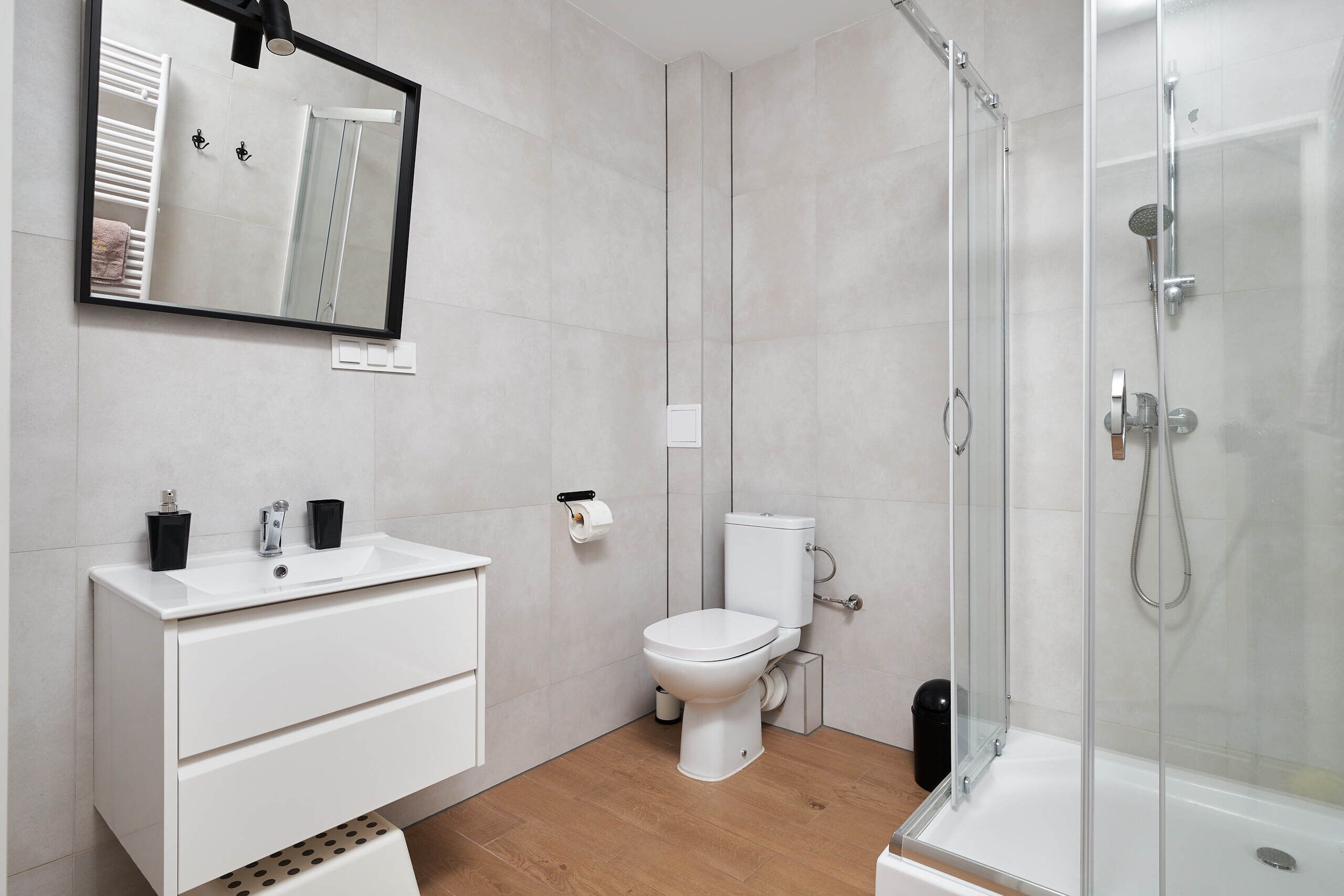 A modern bathroom with a white sink, toilet, and shower.