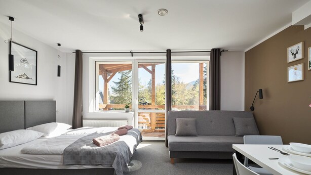 A modern bedroom with a bed, a sofa, and a dining table. - Villa Alpina (Szklarska Poreba)