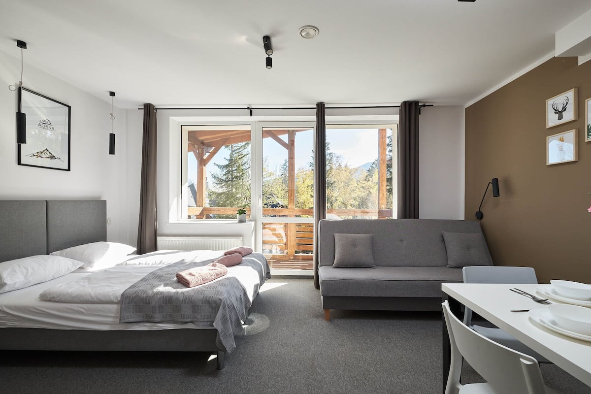 Un dormitorio moderno con cama, sofá y mesa de comedor.
