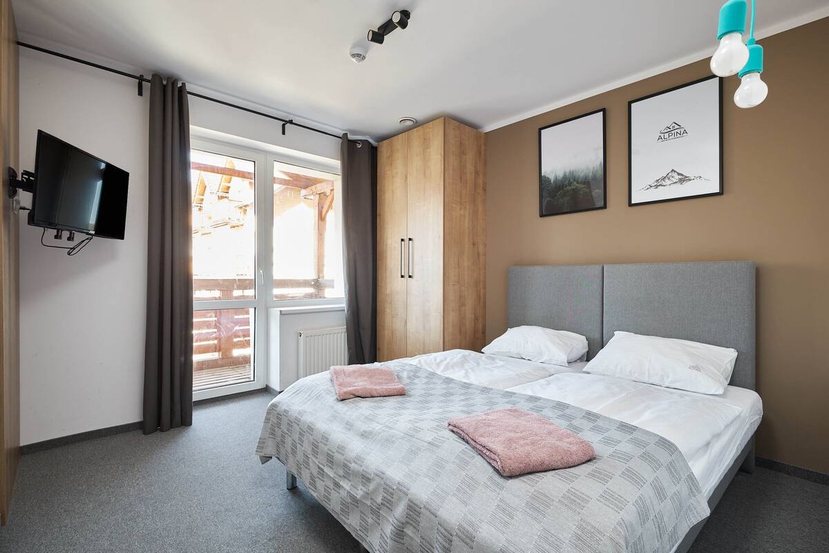 Un dormitorio con dos camas, televisión, armario de madera y cuadros en la pared.