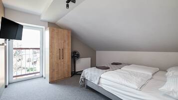 A bedroom with a bed, a wooden wardrobe, a radiator, and a window.