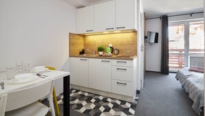 A compact kitchen with white cabinets, a wooden countertop, and a black and white patterned floor. - Villa Alpina (Szklarska Poreba)