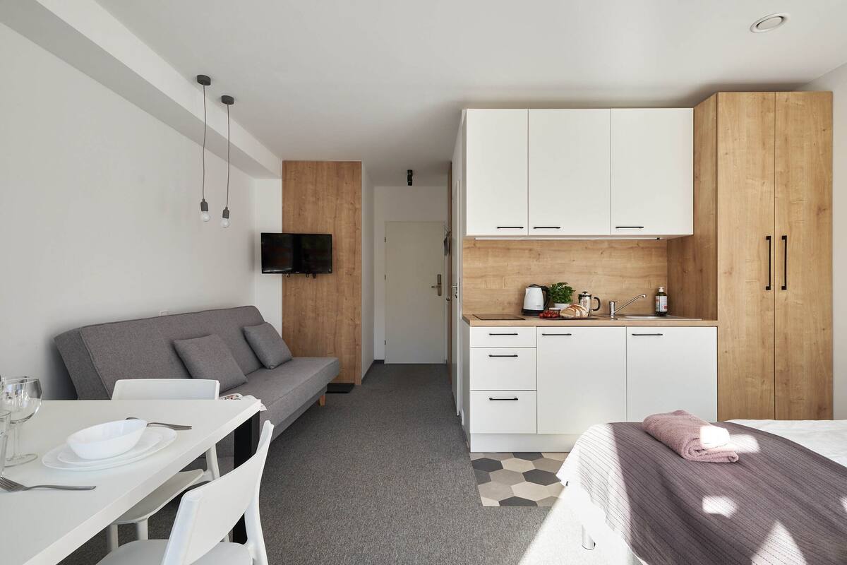 Una habitación de hotel moderna con zona de comedor, kitchenette y sofá.