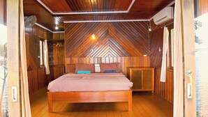 Un dormitorio con techo de madera, una cama con almohadas y una mesita de noche.