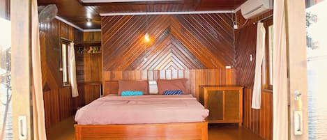 Un dormitorio con techo de madera, una cama con almohadas y una mesita de noche.