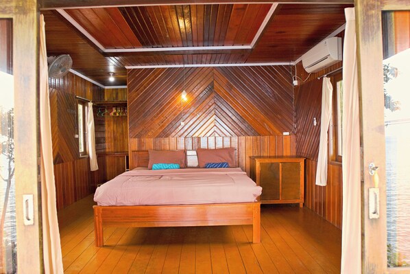 Un dormitorio con techo de madera, una cama con almohadas y una mesita de noche.