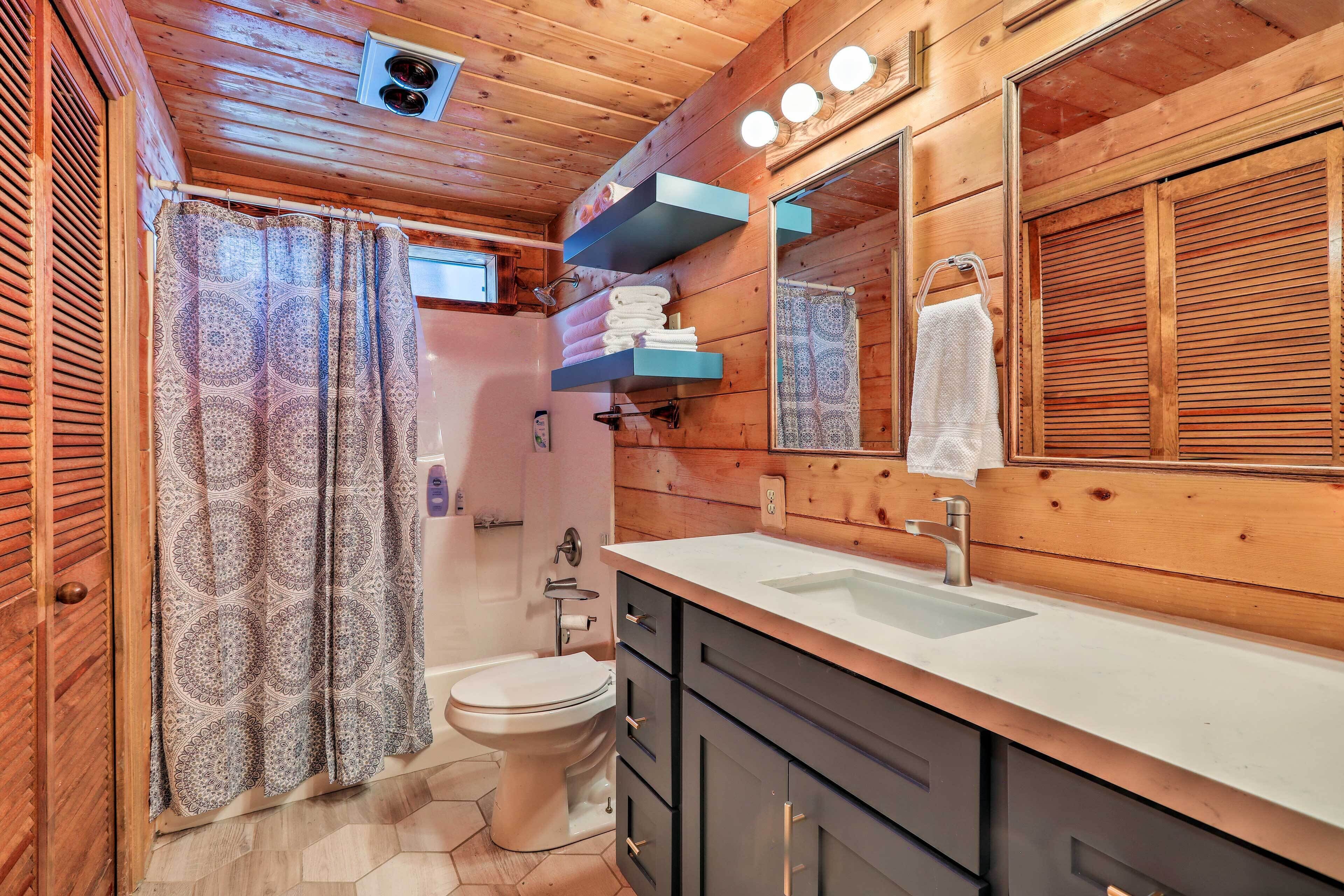 A wooden cabin bathroom with a toilet, sink, and shower.