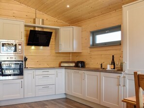 A kitchen with white cabinets, a microwave, a toaster, and a window above the sink.