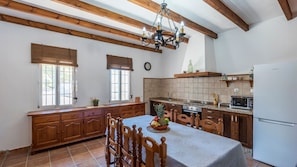 A kitchen with wooden cabinets, a dining table with chairs, a refrigerator, and a microwave.