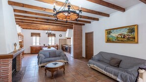 Ein geräumiges Wohnzimmer mit Kamin, zwei Sofas, einem Couchtisch und einer Küche im Hintergrund.