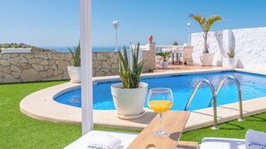 A poolside area with a glass of orange juice, a potted plant, and a view of the sea. - Casa Los Pinos Torrox by Ruralidays (Málaga)