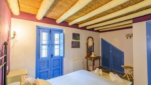 A bedroom with a bed, a blue door, a dresser, a mirror, and a blue wardrobe. - Casa Almijara Cómpeta by Ruralidays (Málaga)