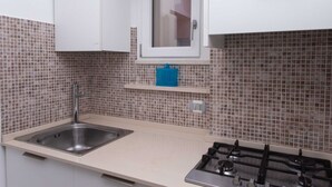 A kitchen with a sink, stove, and a window above the countertop. - S099 - Sirolo, new two-room apartment with wonderful sea view (Sirolo)