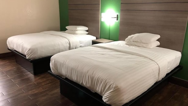 Ein Hotelzimmer mit zwei Betten, einem Nachttisch und einer Wandleuchte.