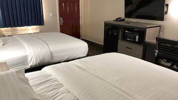 A hotel room with two beds, a TV, a desk, and a door.